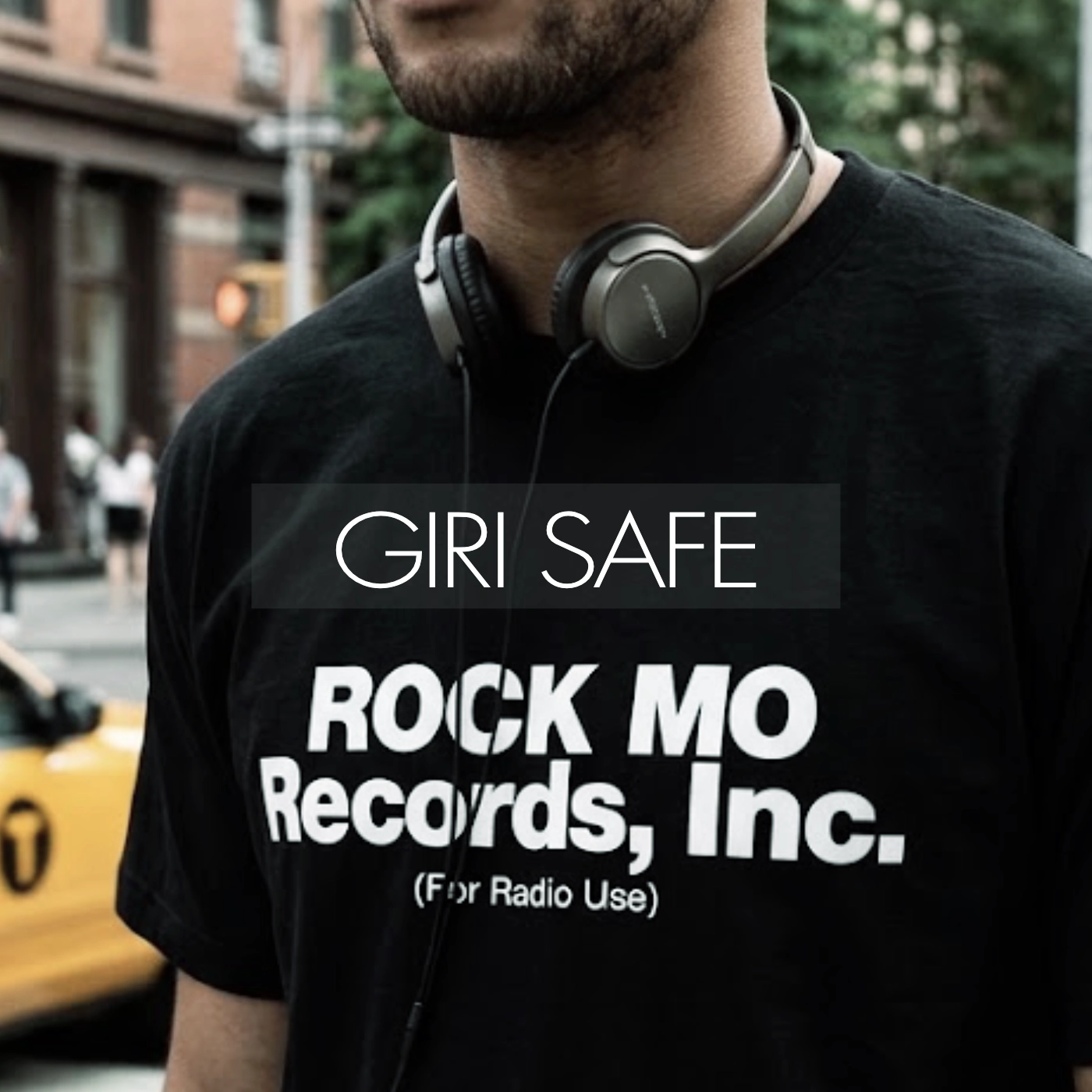A person wearing a record-label logo T-shirt with headphones around their neck